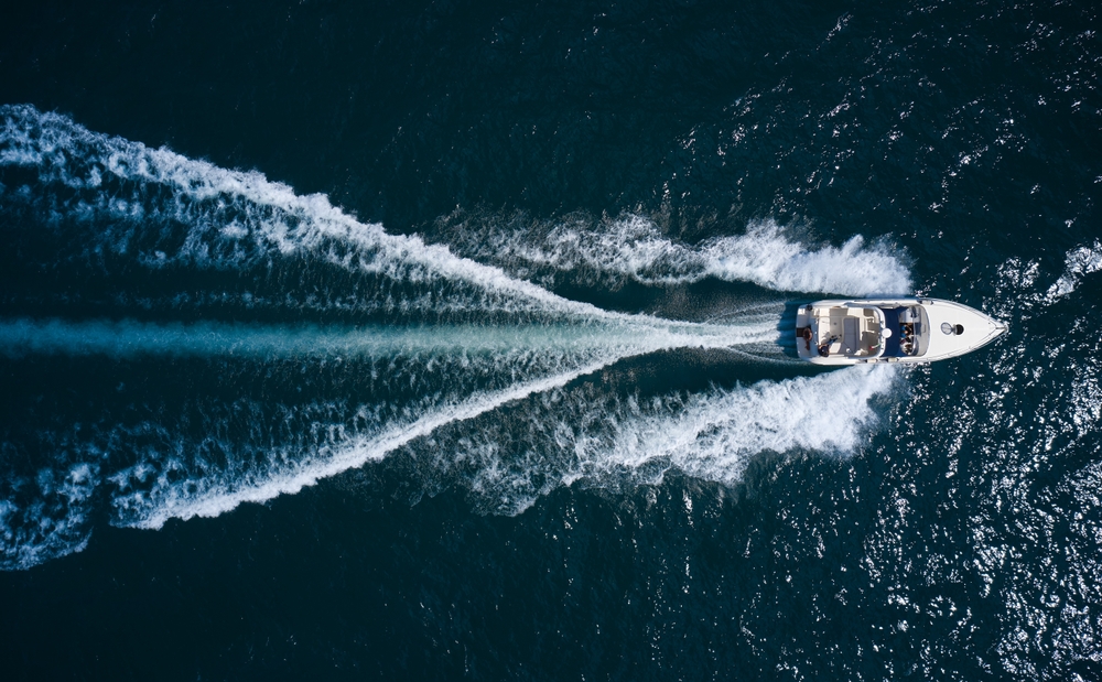 Big,Boat,In,Motion,On,The,Water,Top,View.,Luxury A boat cutting through blue waters
